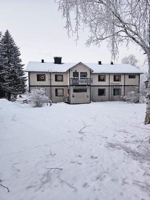 a house with a snow covered yard in front of it at Nietos Aurora in Ylitornio