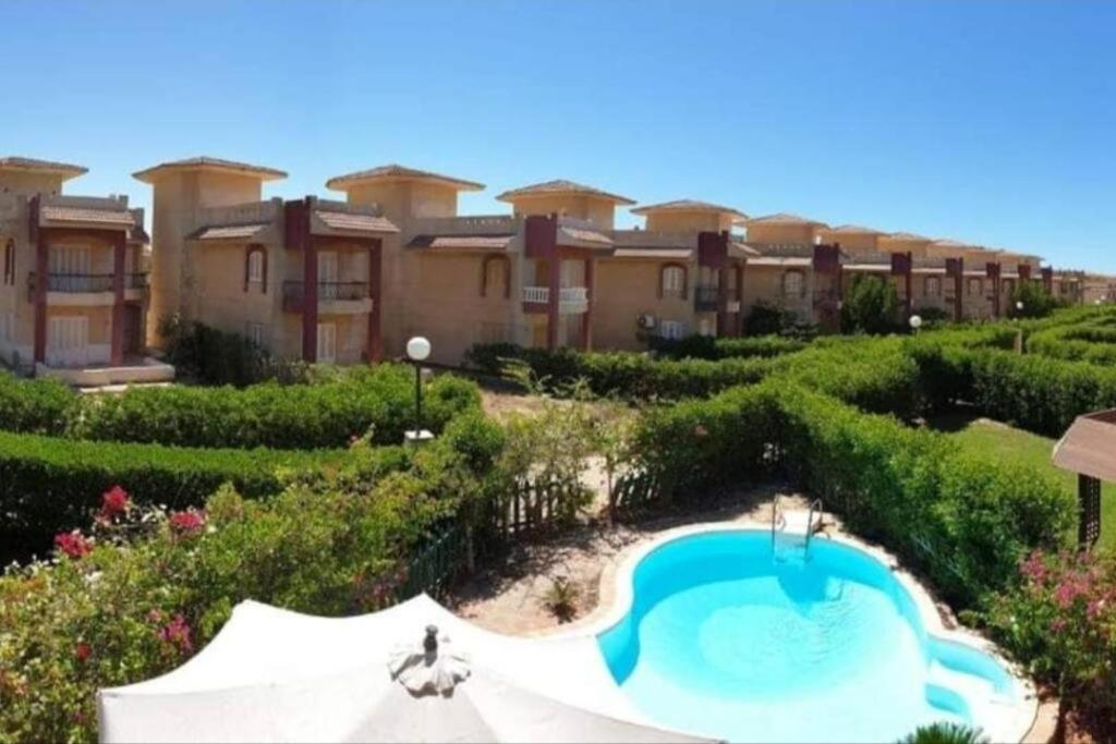 a resort with a swimming pool in front of a building at Spacious Villa with Pool and Sea View in Dawwār ‘Abd Allāh