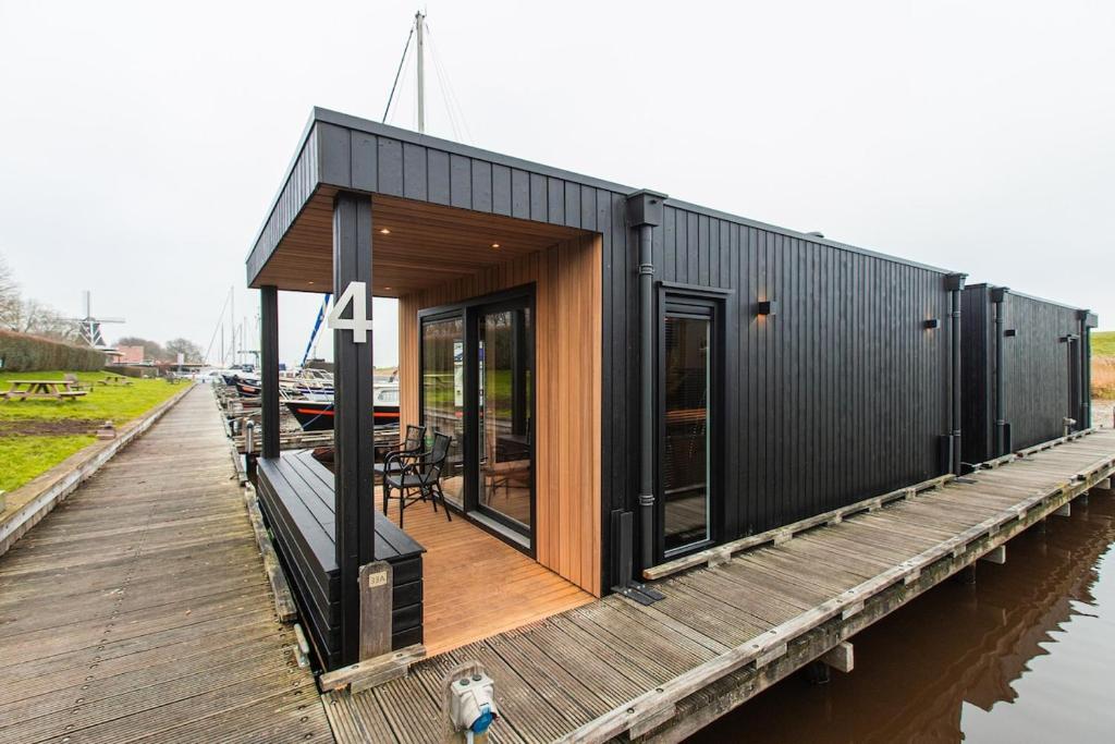 a black house on a dock on the water at Tiny Boat House #6 in Garnwerd