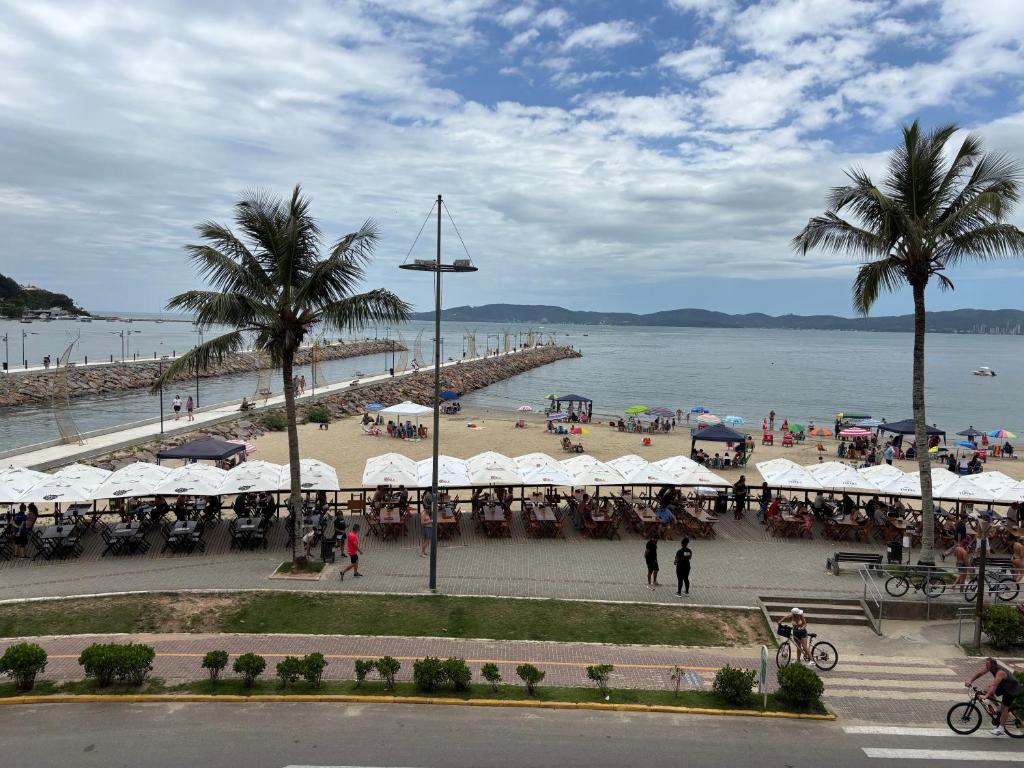 a beach with a group of tables and umbrellas at Vista para o molhe in Itapema