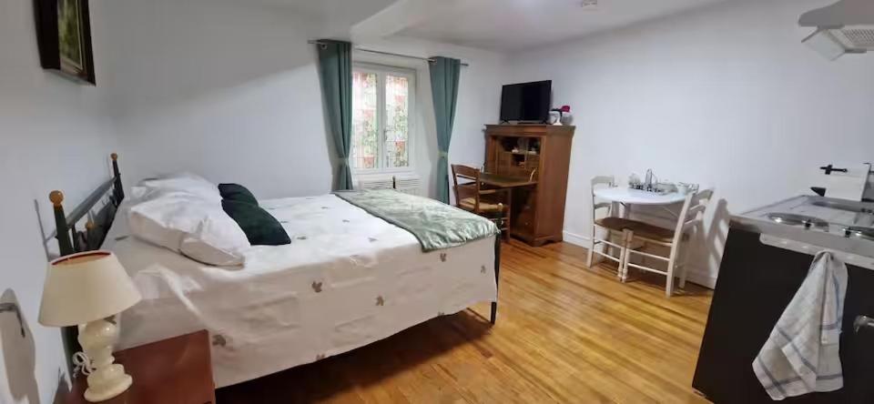 a bedroom with a bed and a desk and a window at Charmant studio - Centre historique de Crémieu in Crémieu