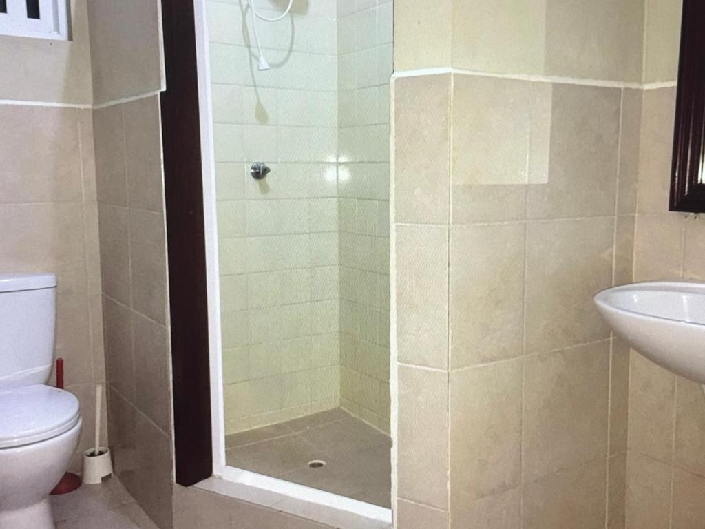 a bathroom with a shower with a toilet and a sink at Ocean Grace - Canouan Island in Canouan