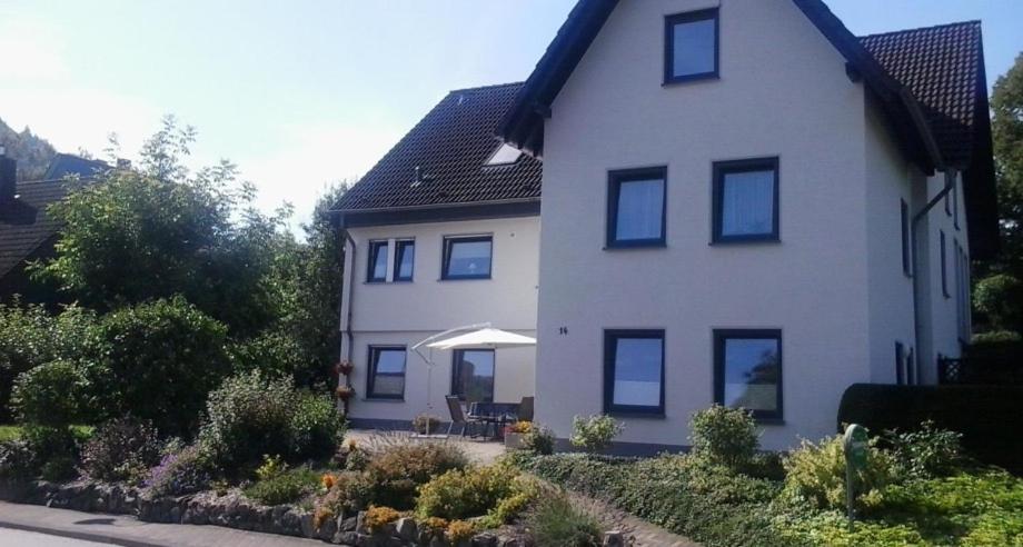 a large white house with a table and an umbrella at Ferienwohnung Hunold in Marsberg