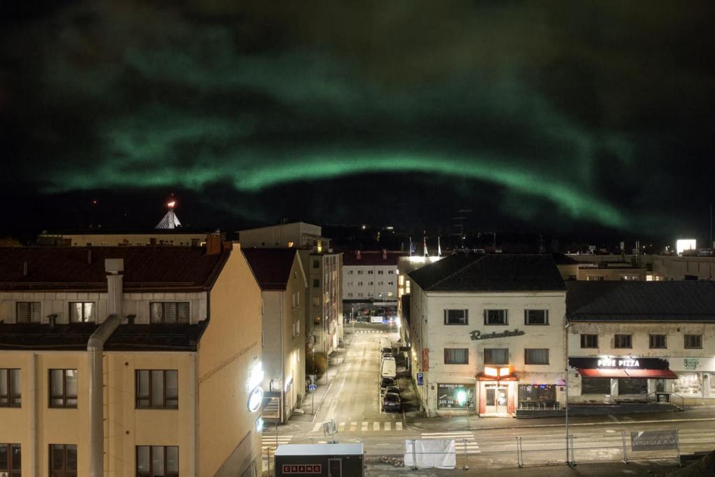 a green light in the sky over a city at night at Aurora Family Suite in Rovaniemi