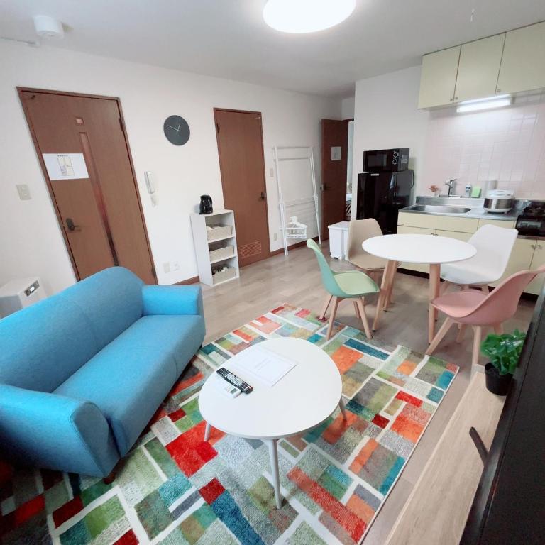 a living room with a couch and tables and a kitchen at Transys three in Chitose