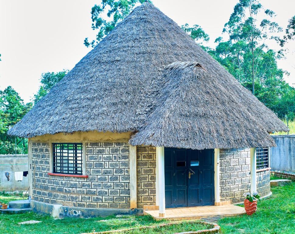 a small brick building with a grass roof at Tropical lodge in Kakamega