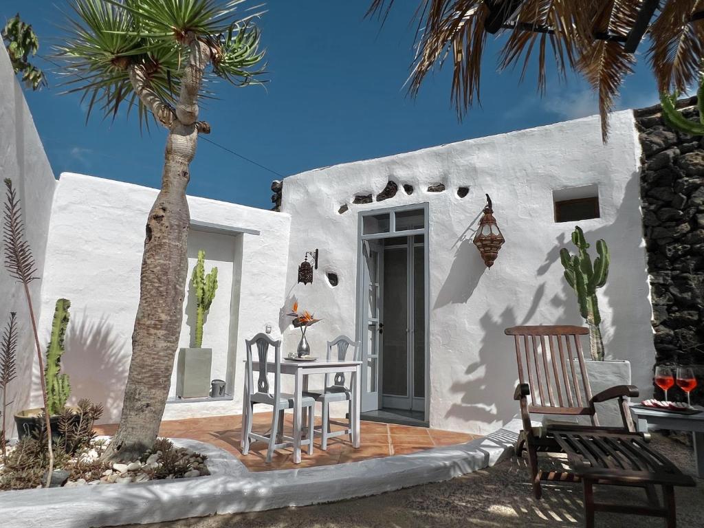 een wit huis met een tafel, stoelen en een palmboom bij Stylish getaway with secluded Patio in lava Finca in Uga