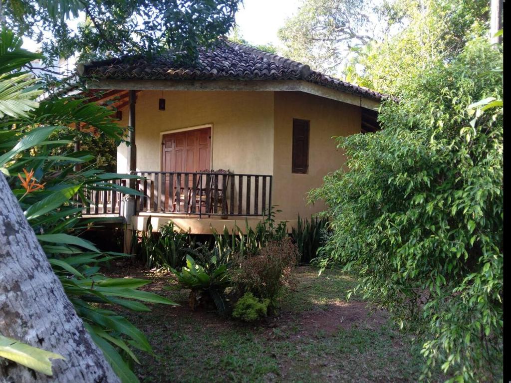 een klein huis met een veranda en een balkon bij Guruwaththa Eco Lodge in Hikkaduwa