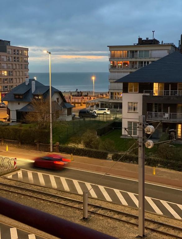 a red car driving down a road in a city at Residentie Sofie in Koksijde