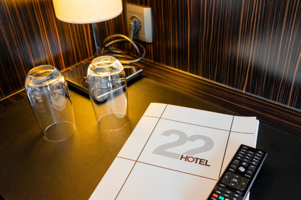 een tafel met twee glazen en een afstandsbediening bij Hotel 22 in Dessau