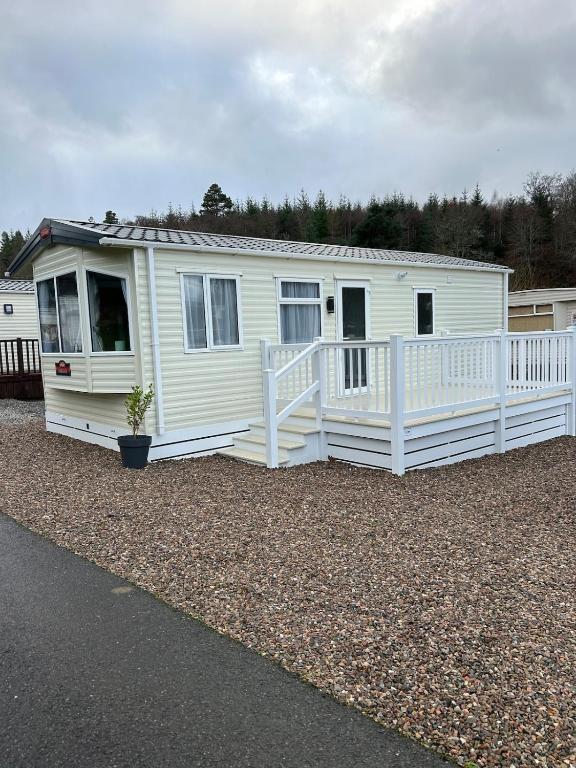 a white house with a porch on a gravel yard at Annas Escape Burnside Moray in Fochabers