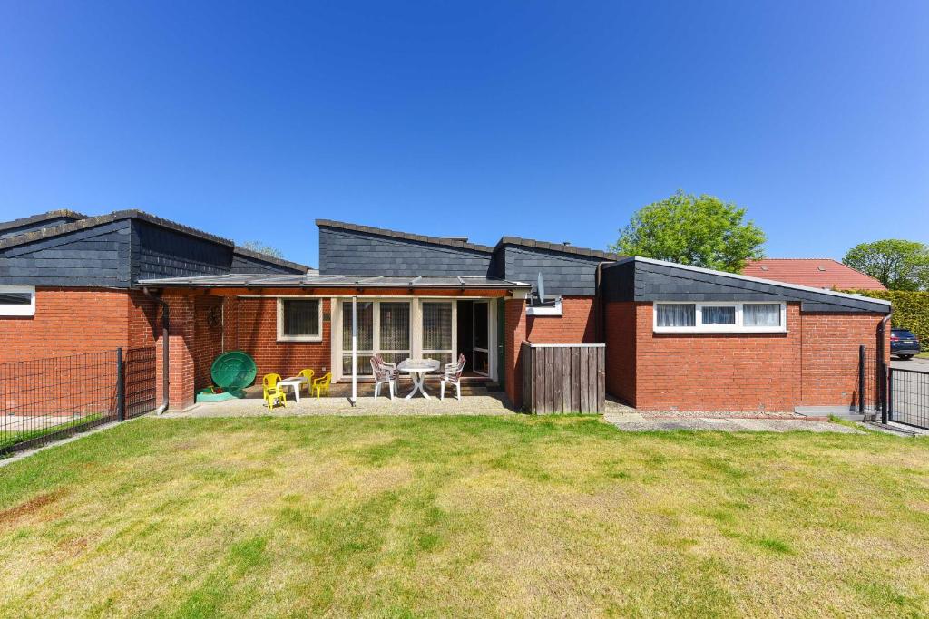 a brick house with a patio and a yard at Ferienhaus Wolke 7 in Bensersiel