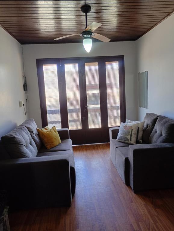 a living room with two couches and a ceiling fan at Aluguel de Temporada in Arroio do Sal