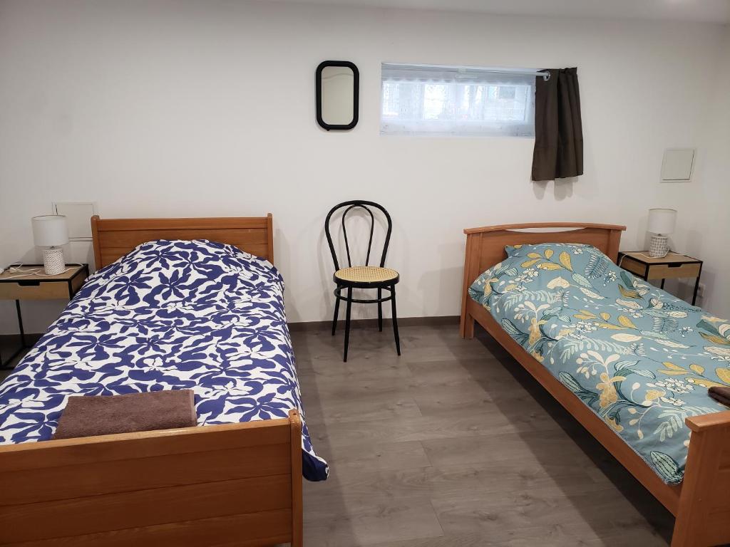 a bedroom with two beds and a chair in it at Chambres d'hôtes en Alsace in Sélestat