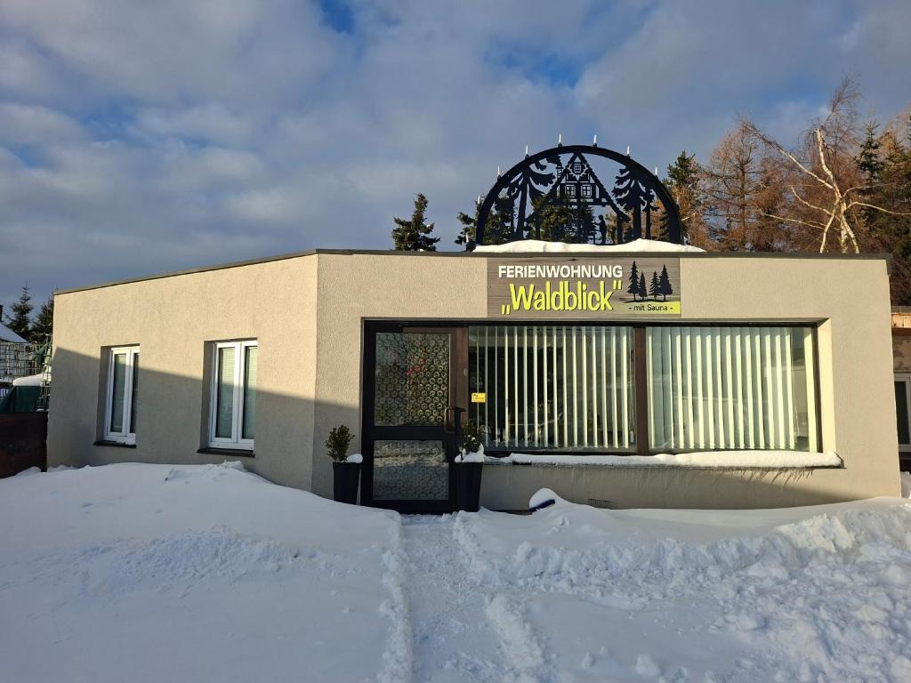 een gebouw met een bord erop in de sneeuw bij Ferienwohnung Waldblick mit Sauna in Deutschneudorf
