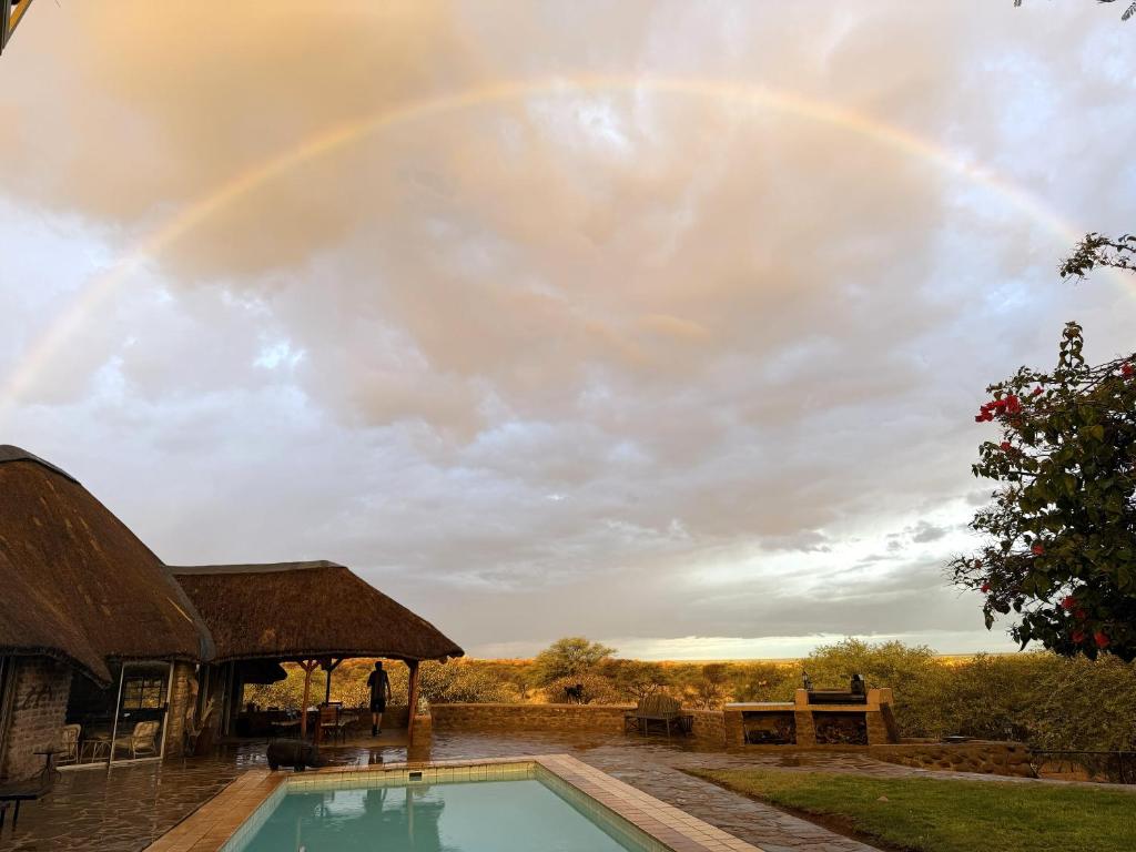 a rainbow in the sky over a swimming pool at Outeniqua Guest Farm in Okahandja