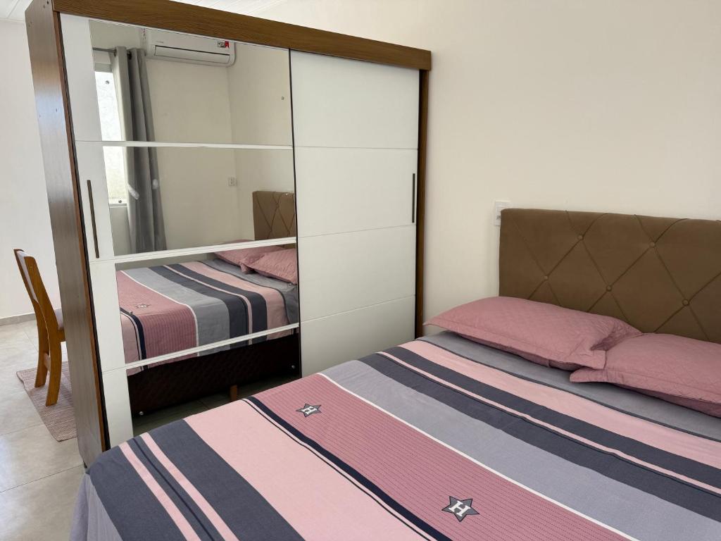 a small bedroom with a mirror and a bed at Loft novo e bem localizado in Biguaçu