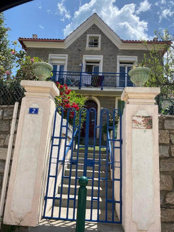 a blue gate in front of a house with flowers at Appartement plein centre avec jardin de 40m2 près des plages in Propriano