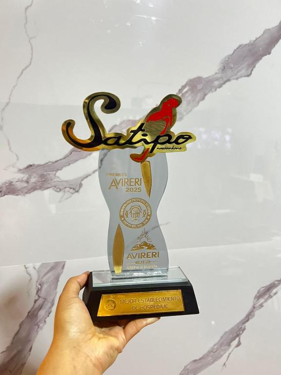 a hand holding up a trophy with a bird on it at Hotel Mayros in Satipo