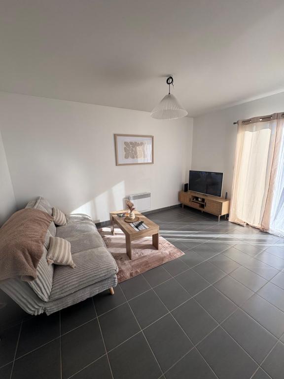 een woonkamer met een bank en een tafel bij Maison entière avec jardin , Proche Bordeaux, Rocade et Arkéa Arena in Bouliac