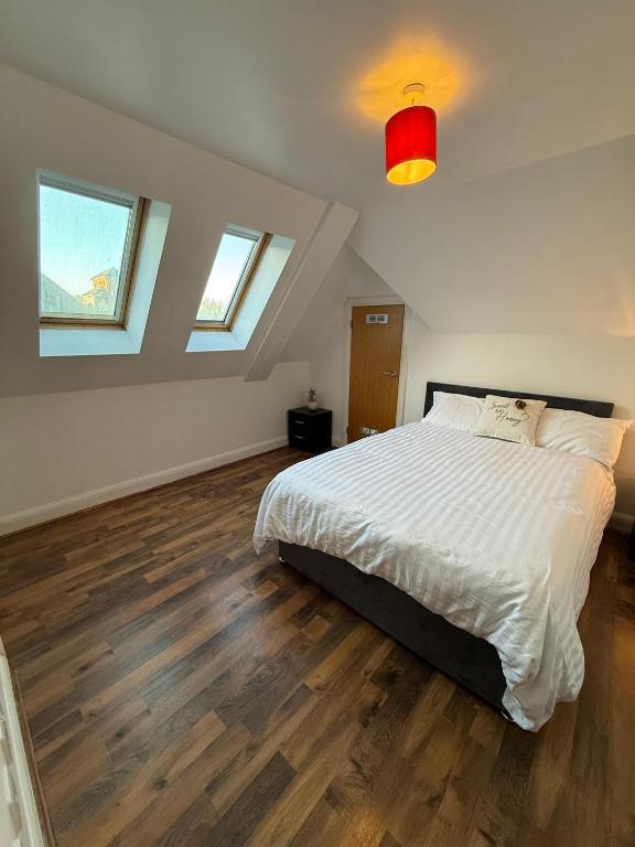 a bedroom with a white bed and wooden floors at Guildford Court Apartment Colchester in Colchester