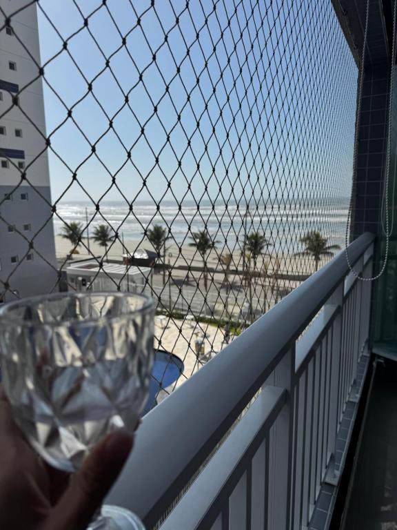 a person holding a wine glass on a balcony overlooking the beach at Refúgio Brisa e Mar in Mongaguá