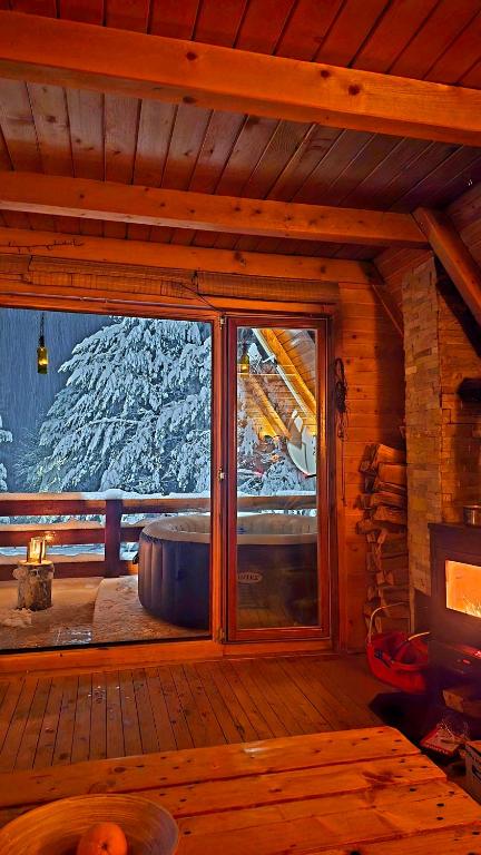 a window in a cabin with a view of a snow covered mountain at Chalet with outdoor jacuzzi near Sarajevo in Pale