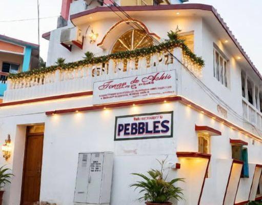 a white building with a sign that reads pebbles at Pebbles Guest House Digha in Digha