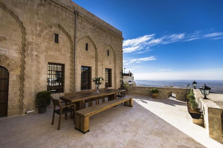 a wooden table and chairs on a patio with the ocean at Birsen Hanım Konağı in Mardin