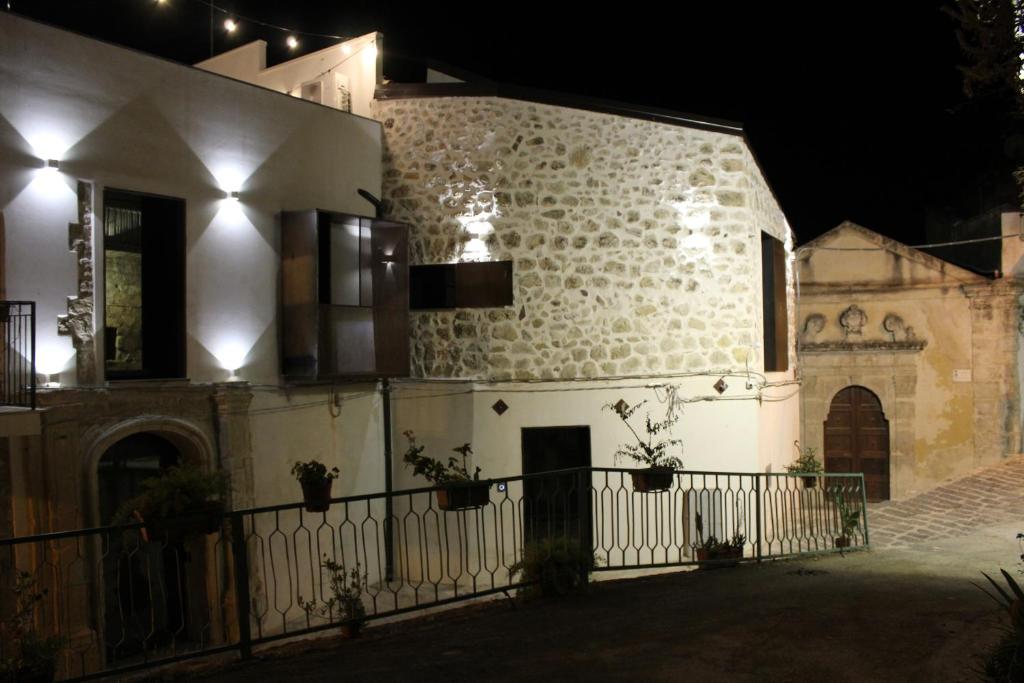a white building with a fence in front of it at night at Le Dimore di San Nicola in Favara