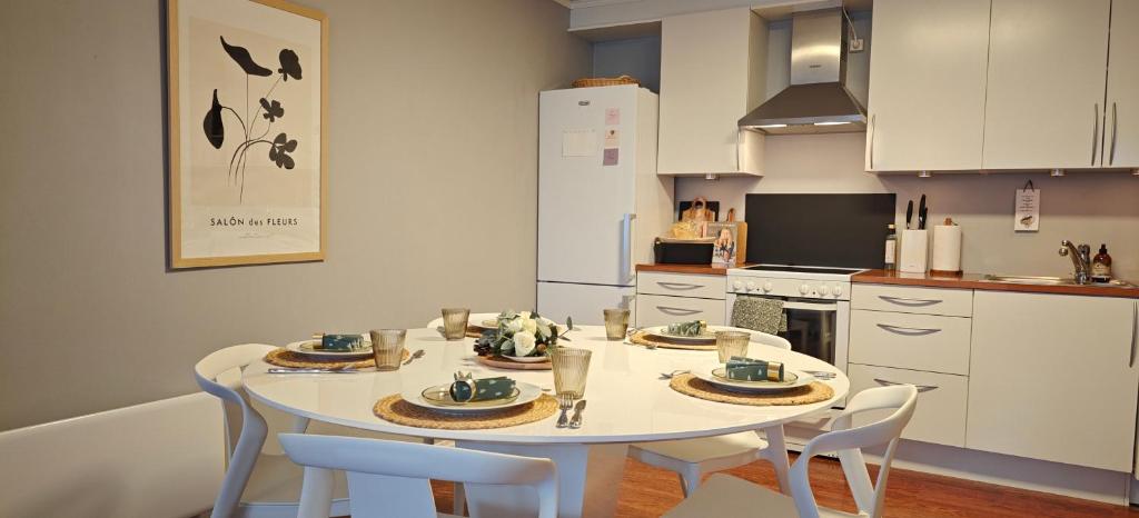 een keuken met een witte tafel en stoelen bij Bright & Spacious Apartment by the Sea, Free Parking, 10min to Airport, 12min to Ålesund in Ytterland