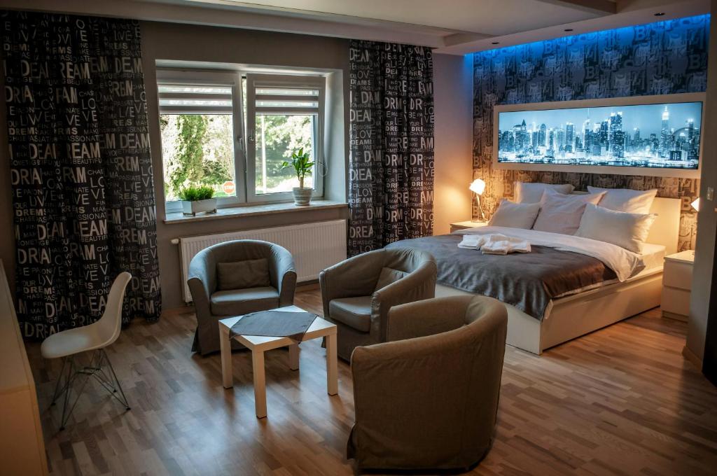 a bedroom with a large bed and two chairs at Brooklyn Noclegi in Jasło