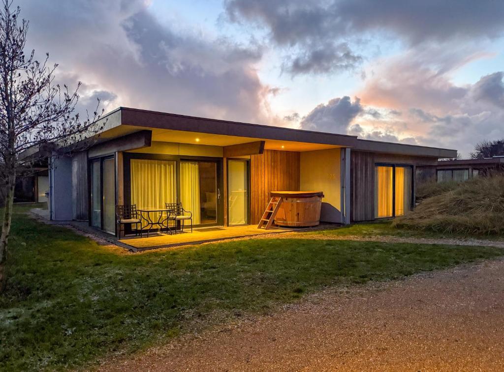 Garden Suites - Duinhotel in Burgh-Haamstede zeeland في برغ هالمستاد: منزل صغير مع طاولة وكراسي في ساحة