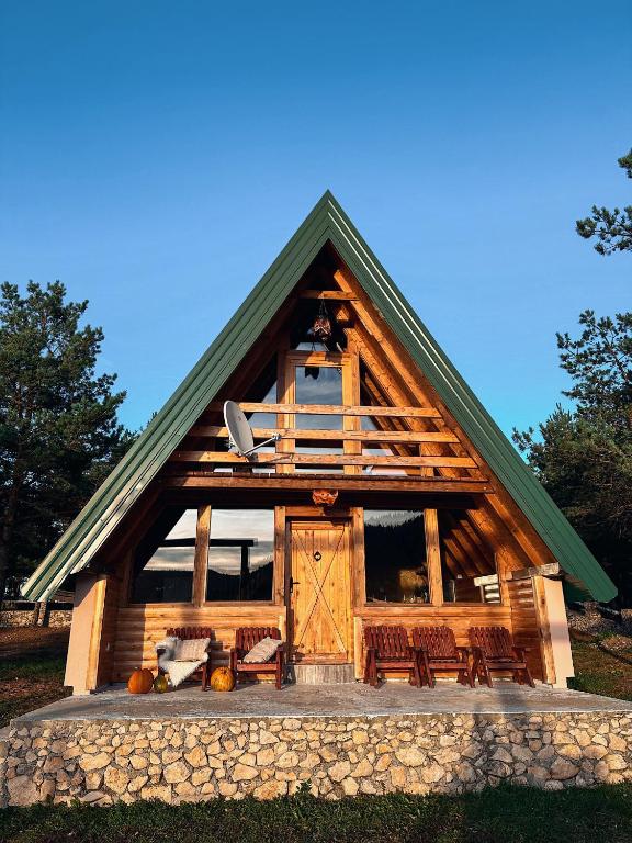 a large wooden cabin with chairs and a porch at Vikendica Pino in Han Pijesak