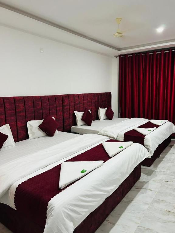 two beds in a room with red curtains at Breezy bluff in Madikeri