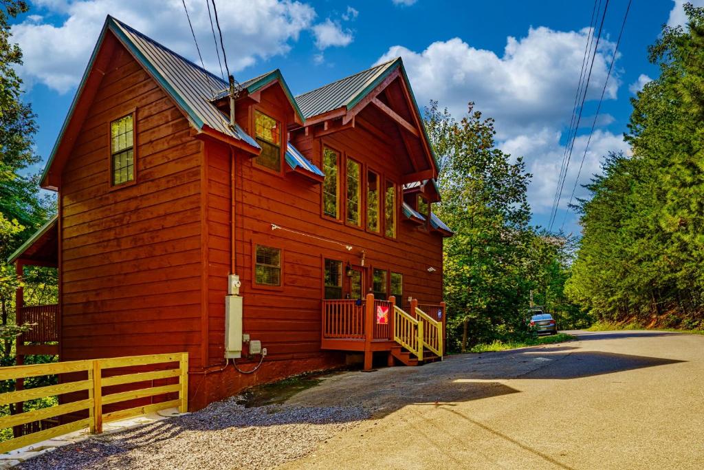 a red house with a fence in front of it at Goonies Cove - Spacious 4BR Cabin Arcade, Pool Table & Hot Tub! in Sevierville