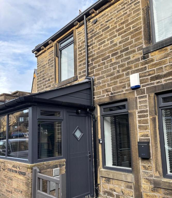 a brick building with a black door and windows at Folly Field in Haworth