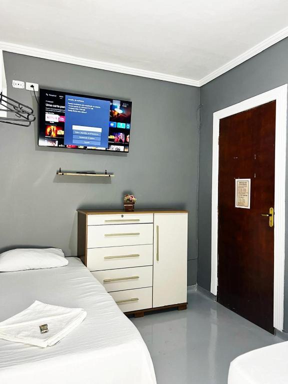 a bedroom with a bed and a tv on the wall at Hostel Anprado #5 Kit café incluso, Próx-Aeroporto de Guarulhos in Guarulhos