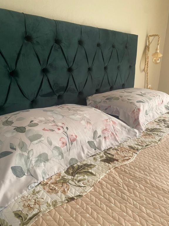 a bed with a blue headboard with a floral pillow at Quarto suíte privativa in Xaxim