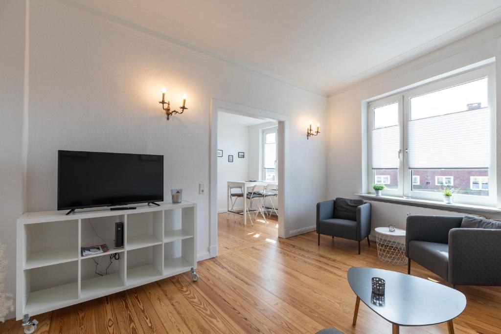 a living room with a flat screen tv on a white shelf at Wohnung Deichbude in Cuxhaven