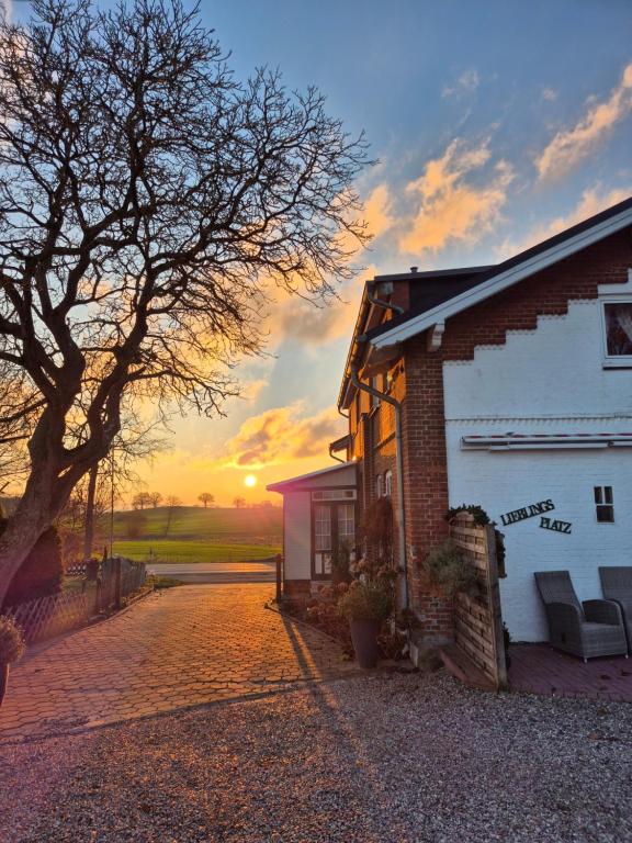 a house with the sun setting in the background at Ostsee Pension Pohnsdorfer Mühle in Sierksdorf