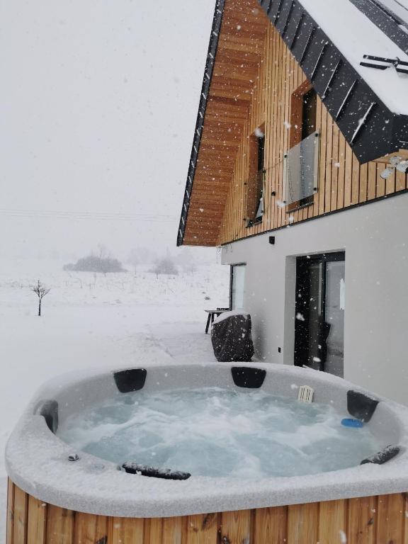 a hot tub in the snow in front of a building at Kącik Na Dolinie in Groń