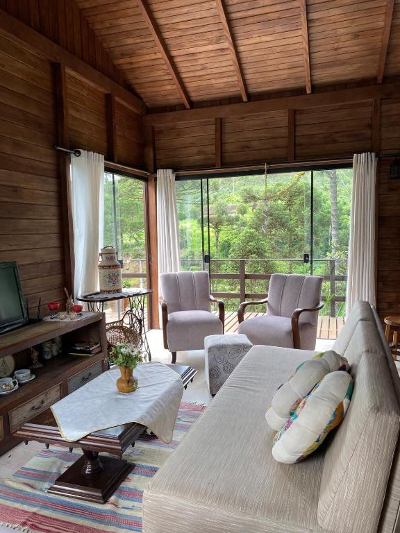 a living room with a couch and a tv and windows at Ebenezer in Benedito Novo