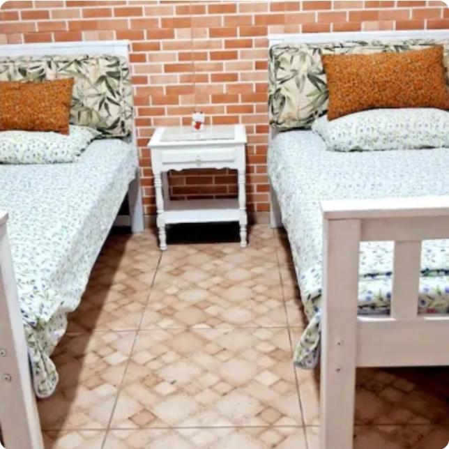 a room with two beds and a brick wall at Varanda Praiana in Rio das Ostras