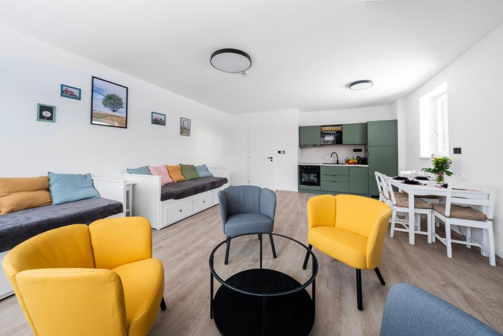 a living room with yellow and blue chairs and a table at Horský sen - Mountain Dream Apartment B1 in Špičák