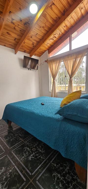 a bedroom with a bed with a blue comforter and a window at Cabaña El Quisco 2do piso con estacionamiento in El Quisco