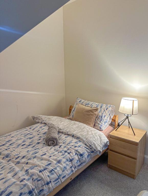 a bedroom with a bed and a lamp and a nightstand at The Calm Space Room in Balderton