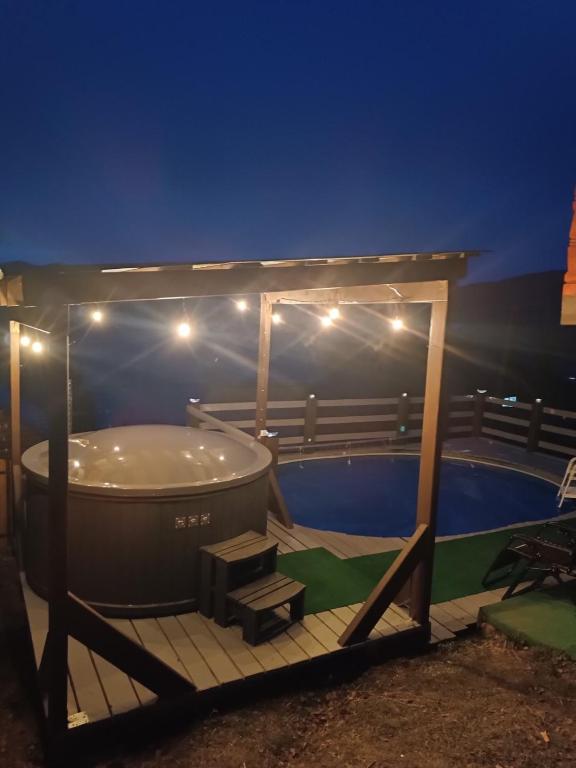 a hot tub on a deck next to a pool at night at Сімейний котедж КРАЄВИД чан джакузі сауна in Mykulychyn