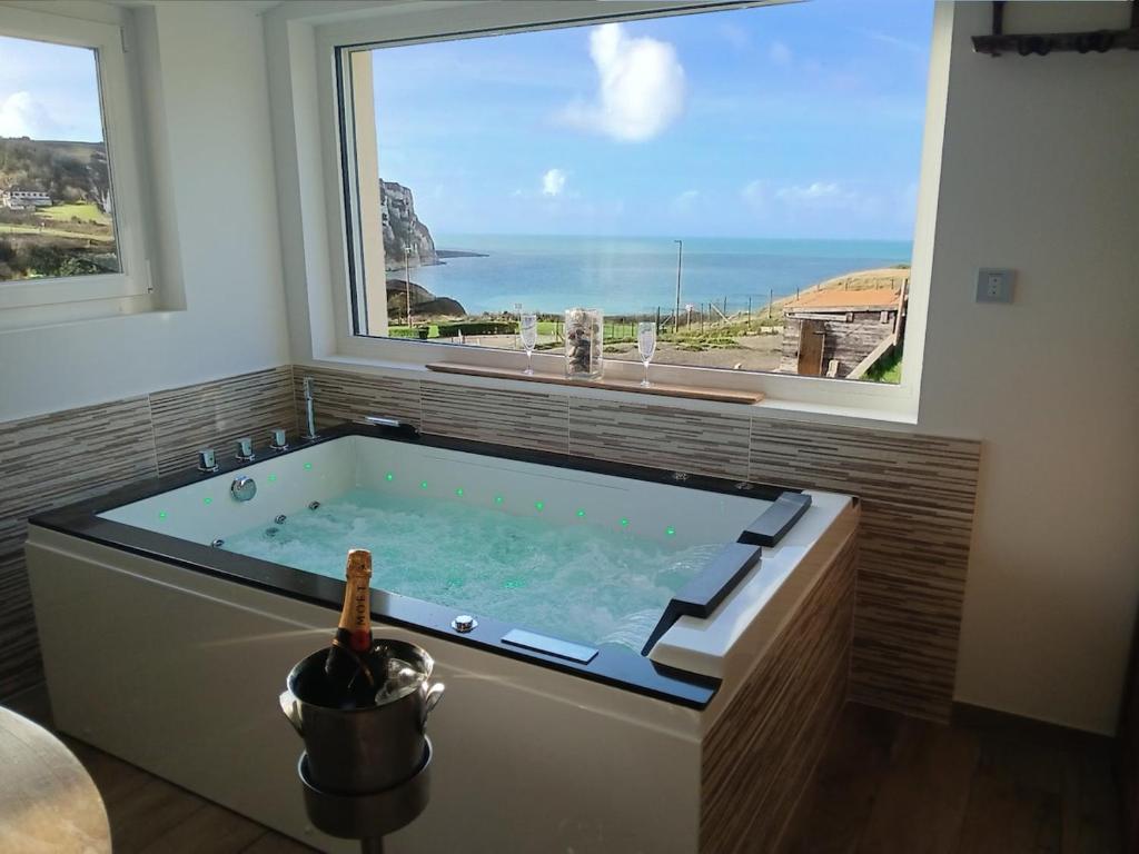a large bath tub in a room with a large window at L'Effet Mer - Côte D'Albâtre in Saint-Martin-Plage