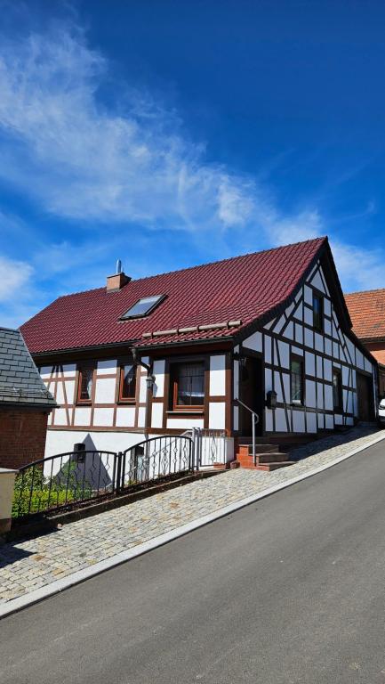 a white and black house with a red roof at Ferienhaus Am Arzberg in Kurort Steinbach-Hallenberg